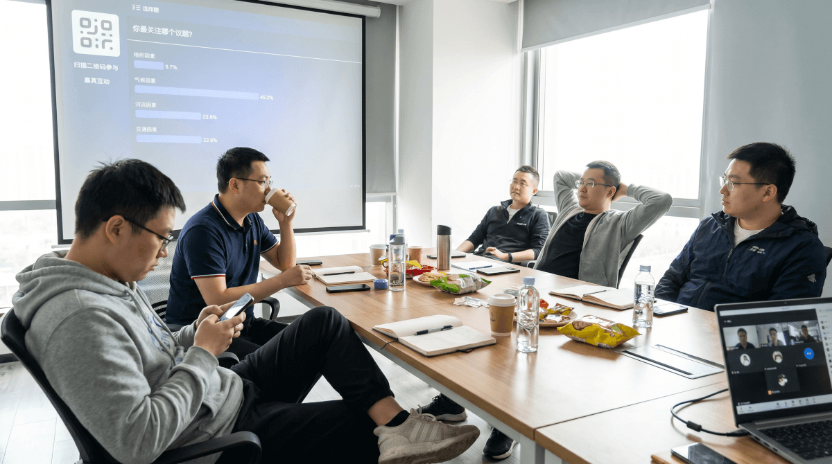 混合会议场景,会议室大屏显示实时投票结果,部分参会者通过手机参与互动